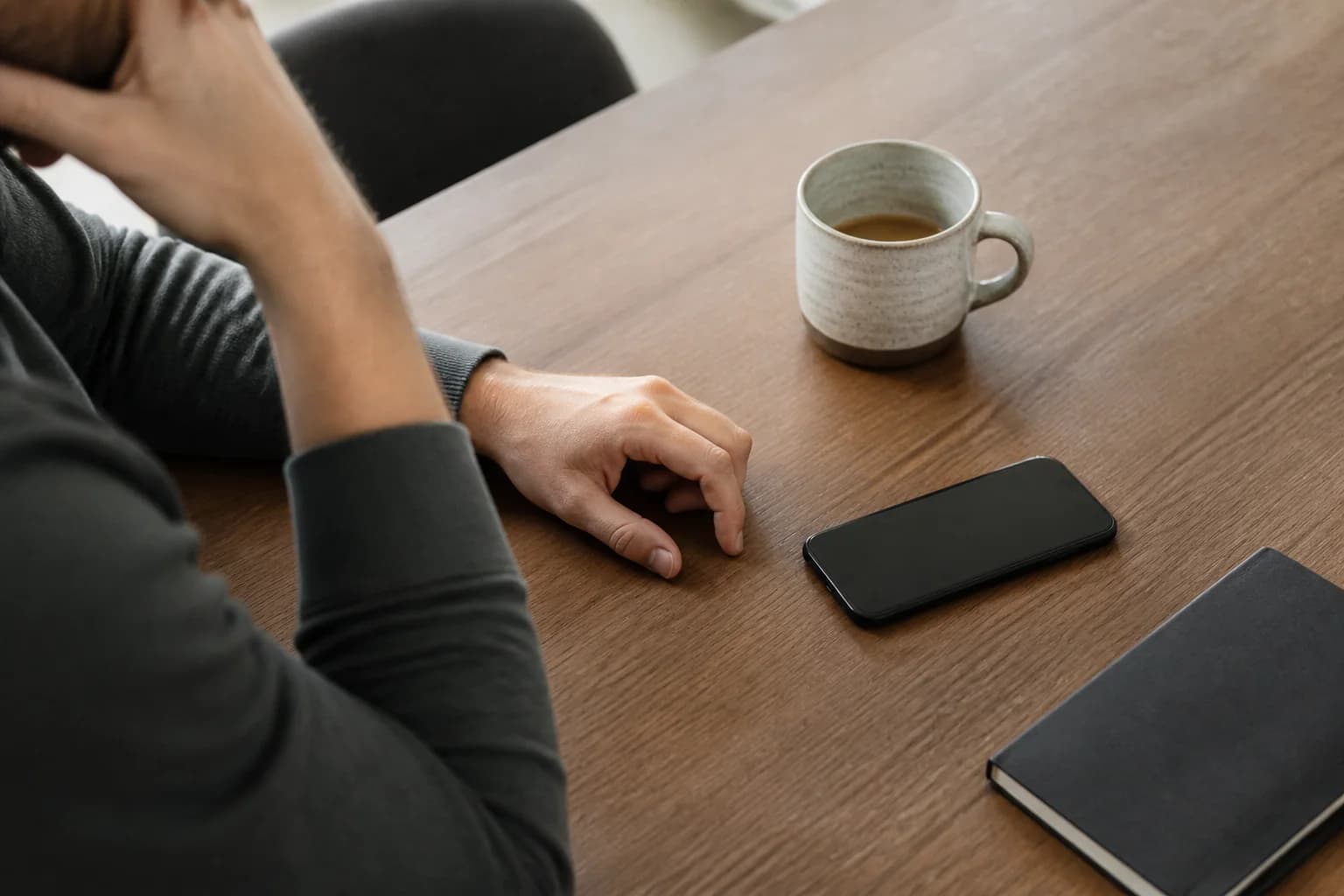 A phone resting face down beside coffee and a notebook
